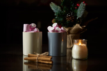 Cozy warm drinks with marshmallows and candlelight for winter evenings