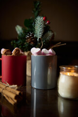 Warm holiday drinks in mugs with marshmallows and festive decorations