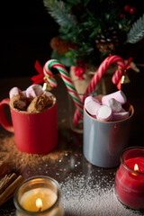 Festive hot chocolate with marshmallows and candy canes by candlelight