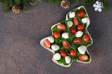 Italian Caprese salad with cherry tomatoes and mozzarella cheese served in plate as Christmas tree, Top view