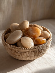Smooth stones in a woven basket, bathed in warm light.