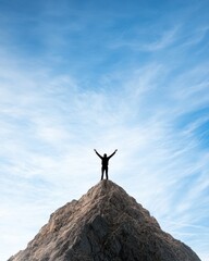 Silhouette of a Person Standing on a Mountain Peak Against Sky