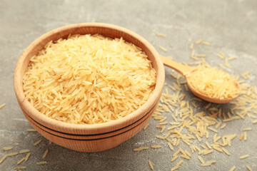 Rice grains on brown plate and spoon on grey concrete background