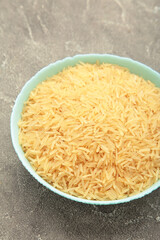 Rice grains on mint plate on grey concrete background. Vertical photo