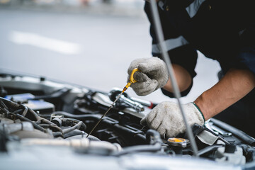 A mechanic is working on a car engine, checking the oil level and adding more if necessary. Concept...
