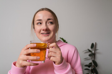 Young girl with braces holds cup with tea at the kitchen