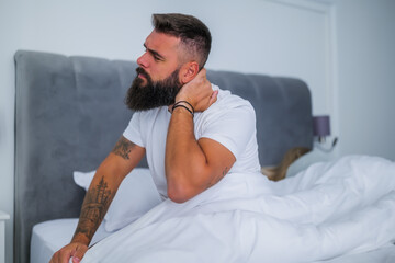 Young couple is sleeping in bed. Man is waking up for work. He has pain in his neck.