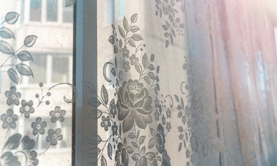 Delicate floral curtains gently filter sunlight, creating a warm and inviting atmosphere in a cozy home