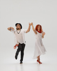 Passionate salsa duo perfects their dance moves, against white studio background, focusing on...