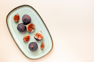 Plate with fresh ripe figs whole and slices on table. Top view