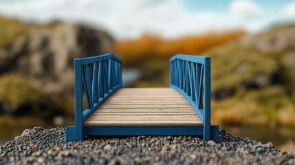 The handmade woodwork. Miniature blue bridge over pebbles with blurred nature background.