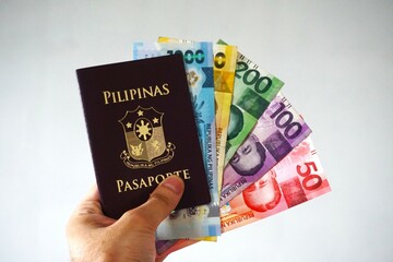 Filipiński paszport z walutą peso w środku, symbolizujący podróże i międzynarodowe połączenia. Pieniądze jako element związany z Filipinami i kosztami podróży.