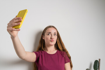 Young beautiful girl uses modern smartphone at home