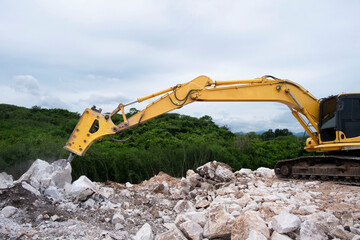 Excavator breaking and drilling stone in quarry. Large pneumatic jack hammer mounted on the...
