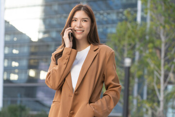 A thinking Asian Female worker works outdoors, showcasing leadership and a happy attitude. An Asian woman, a true leader, works happy