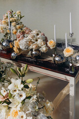 Close-up of elegant wedding floral arrangement on a vintage wooden table with candles and metallic spheres.