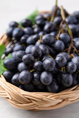 Black grapes in basket on white table, Seedless grapes