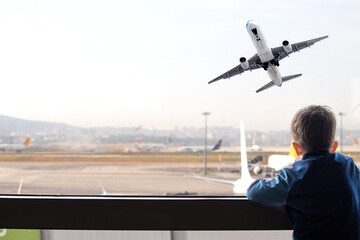 Curious boy watches the plane take off. A tourist kid waits for his flight at the airport. Air...