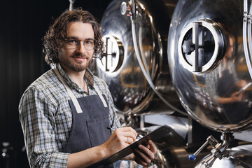 Happy worker man with clipboard control brewery process. Portrait owner of craft beer factory...