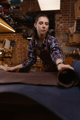 Woman tailor artisan work with rolls brown color leather