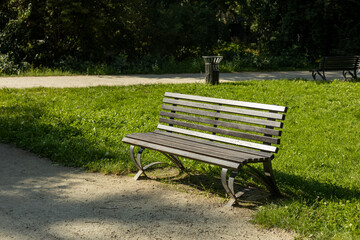 A modern wooden bench with trash bin standing in the park. Comfortable bench in recreation area....