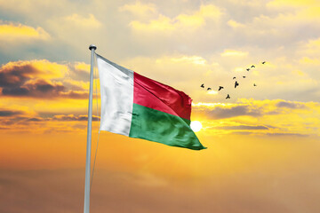 Waving flag of Madagascar against sunset or sunrise. Madagascar flag for Republic Day and Independence Day.