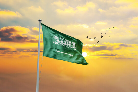 Waving flag of Saudi Arabia against sunset or sunrise. Saudi Arabia flag for Republic Day and Independence Day.