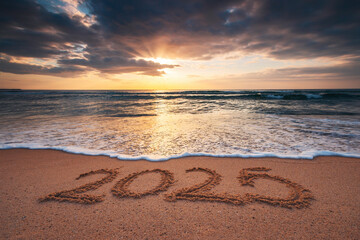 Happy New Year 2025 nature landscape text lettering on the beach sand at sunrise