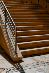 Concrete stairs leading up to the street, in the rays of the daytime sun with contrasting shadows