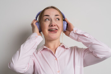 Modern woman smiling with braces on her teeth and listening to music in headphones