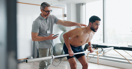 Physiotherapy, fitness and monitor with man in clinic for biofeedback, muscle stimulation and track...