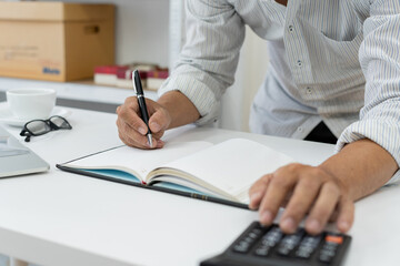 accountant reviews financial data using a calculator at desk in a busy office, ensuring accuracy in tax reporting and financial management.