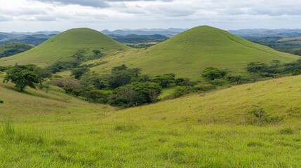 Lush Green Hills Surrounded by Vast Landscape Under Cloudy Sky