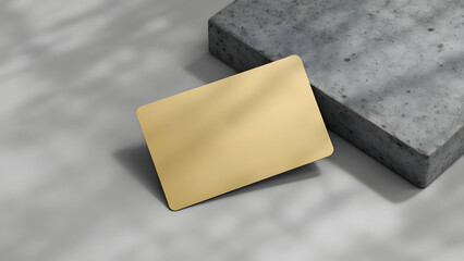 A minimalist image showcasing a blank gold card on a grey concrete block. Soft lighting and shadows add depth. Perfect for branding or design presentations.