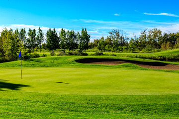 A golf course with a green grassy field and a blue flag
