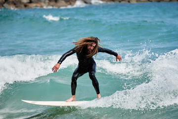 Long-haired bearded surfer on board riding waves