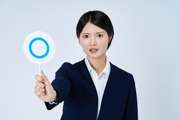 マルのプレートを持つスーツ姿の女性