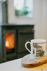 A mug with a picture of a vending machine on it sits on a wooden cutting board next to a fireplace