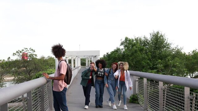 Group of students walks on a bridge, laughing and pointing at another student leaning against the railing, highlighting the dynamics of bullying and social exclusion