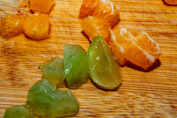 Detalle de trozos de mandarina y uvas verdes sobre una tabla de madera con textura natural