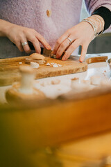 A woman is making food on a wooden cutting board. She is wearing a purple shirt and a black bracelet