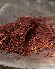 A woman in Oaxaca Mexico manually producing organic chocolate on a metate, an ancient stone tool for grinding food products.