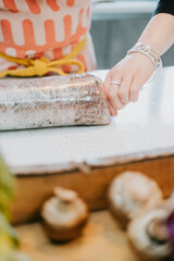 A woman is rolling out dough on a counter. There are several cupcakes on the counter, and a box of mushrooms