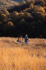 Two smiling woman hiking at top of the hill at meadow.