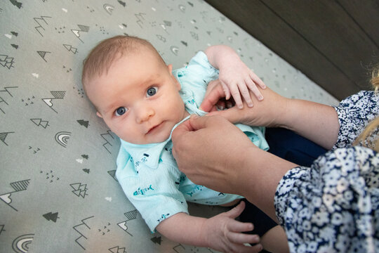 Overhead view of a woman dressing a baby boy lying in a cot