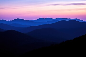 Fototapeta premium mountain range at twilight with peaks fading into layers of soft shadows under glowing sky