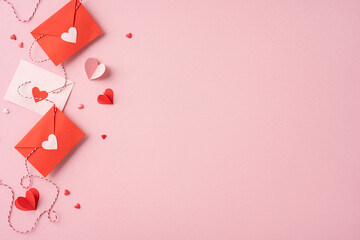 Red and pink paper envelopes with heart decorations on a pink background, symbolizing love and...
