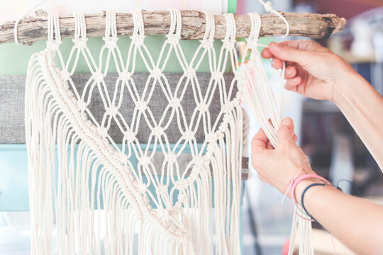 Close-up of a woman weaving a macrame craft product