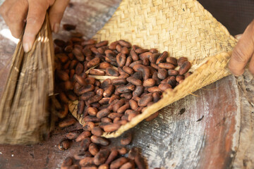 A woman in Oaxaca Mexico roasting cocoa beans on a comal in a wood-burning stove.