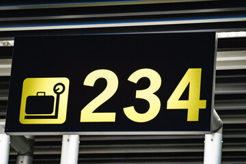 Obraz premium Yellow baggage claim sign with a luggage symbol and the numbers 234